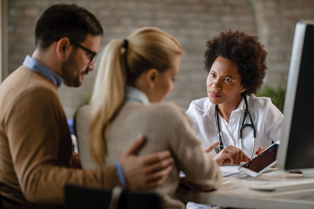 A doctor talks to a couple in an office.