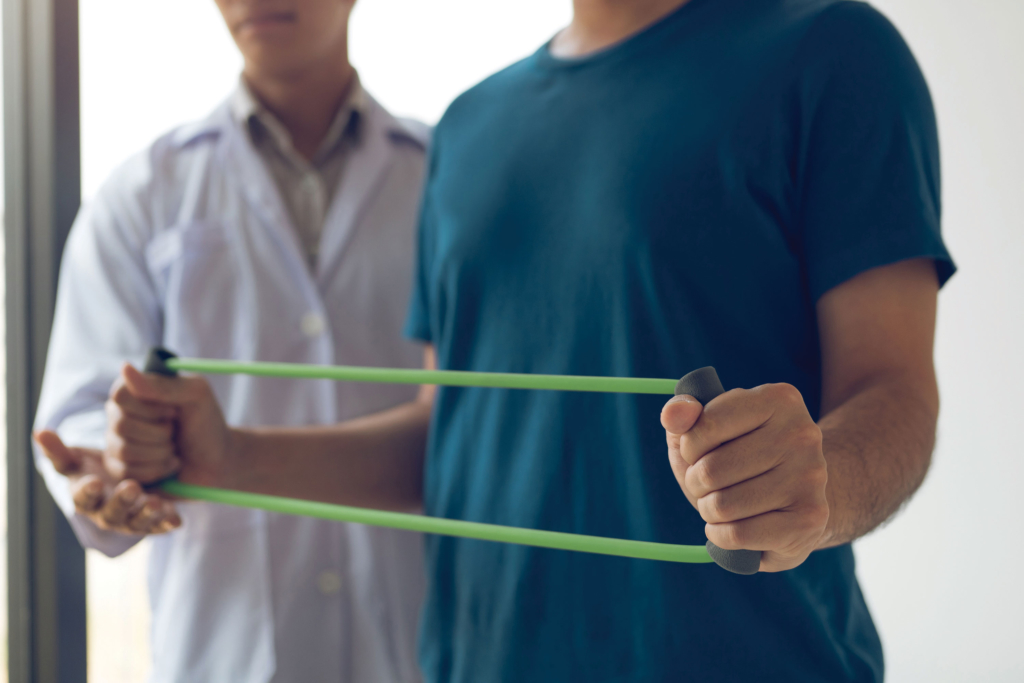 A person uses a physical therapy band while a medical professional assists.