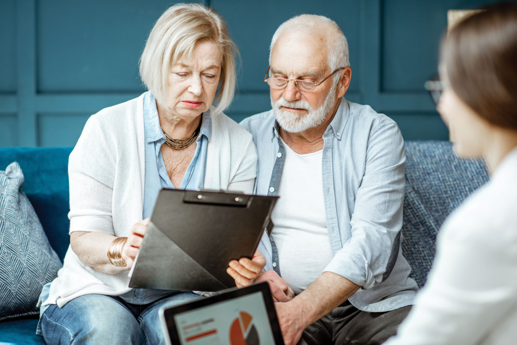 A senior couple reviews a document on a clipboard.